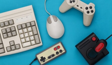 old keyboard, joystick, gamepads and pc mouse on blue background. retro gaming. 80s. top view