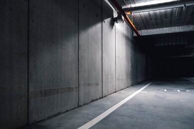 sci fi looking dark and moody underground parking lot with fluorescent lights on. long hall