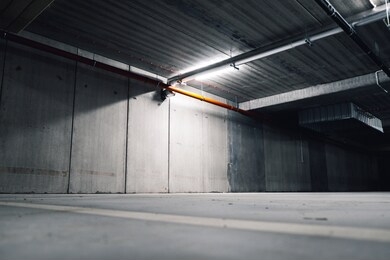 sci fi looking dark and moody underground parking lot with fluorescent lights on. long hall