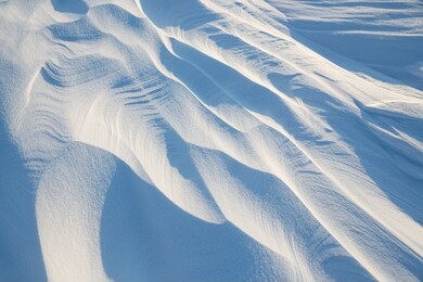 snow texture. wind sculpted patterns on snow surface. wind in the tundra and in the mountains on the surface of the snow sculpts patterns and ridges (sastrugi). arctic, polar region. winter background