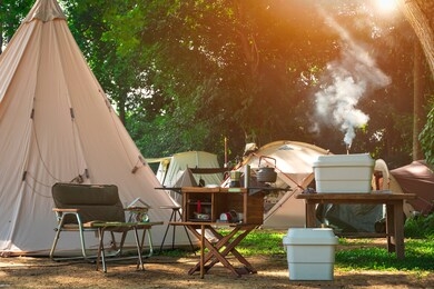 outdoor kitchen equipment and wooden table set with field tents group in camping area at natural parkland