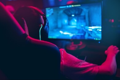 professional gamer playing online games tournaments pc computer with headphones, blurred red and blue background.