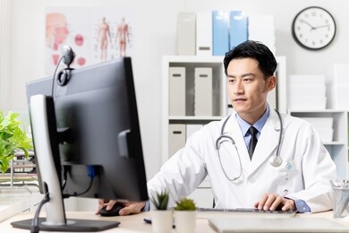 asian young doctor work and type something in computer at the clinic