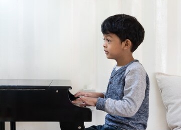 asian japanese kid learning piano in the classroom.