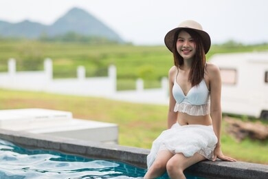 portrait young beautiful asian woman happy smile and relax in swimming pool around hotel resort green yard background for leisure travel in holiday vacation