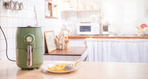 air fryer machine cooking potato fried in kitchen. lifestyle of new normal cooking. technology eco friendly home smart device. air fryer machine with french fried concept