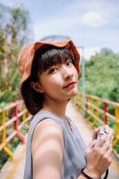 beautiful young asian thai woman traveler posing with camera at country side. local trip in bangkok.