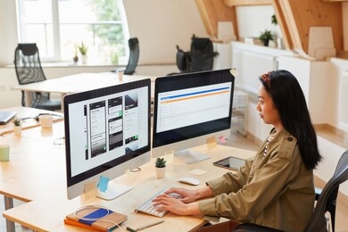 asian young woman sitting at the table typing on computer keyboard she testing new software at office