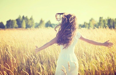 beauty girl outdoors enjoying nature. beautiful teenage model girl in white dress running on the spring field, sun light. 