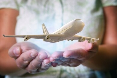 a plane airliner over woman's hands in a protective position. aircraft industry concepts, airline safety and insurance 