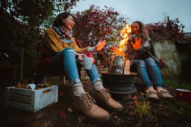 two friends relax comfortably and drink wine on an autumn evening in the open air by the fire in the backyard. the concept of autumn, friendship. top view of the legs