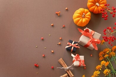 autumn composition with orange pumpkin ,pine cones, cinnamon sticks, flowers and small gifts.
flat lay, top view.
