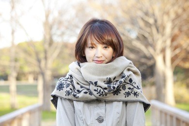 japanese woman smiling while putting on a scarf,