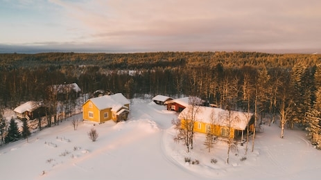 aerial view from drone of landscape in white snow near small cozy village with colorful houses on north, bird’s eye view of lapland countryside land with scenery environment 

