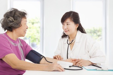 doctor measuring blood pressure of senior woman at home