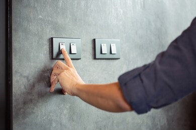 the young man's hand turned off the light switchenergy saving concept