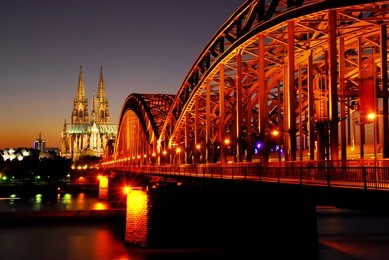view on the 'dom' cathedral and the floodlighted 'hohenzollern' railway bridge over river rhine in cologne at night