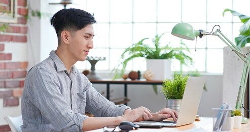 telework concept - sideview of asian man use computer to work and has a video meeting at home