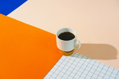 cup of espresso coffee with shadow on colorful bright orange, blue and white background. good morning concept. minimalism. empty space for text.