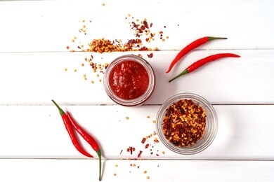 hot chilli pepper sauce paste harissa, traditional tunisia, moroccan, arabic cuisine adjika ,chili pepper spices and fresh red chilli peppers, over white wooden background,flat lay.