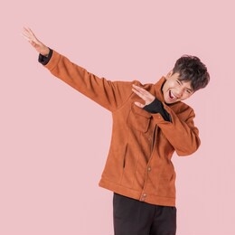 portrait of asian handsome young man in fashionable clothing and enjoy standing with gesture dab dance isolated on pink background.