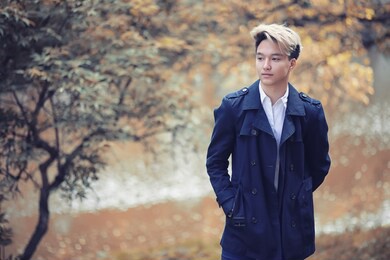 autumn park in rainy weather and a young man with an umbrella
