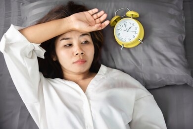 sleepless asian woman insomnia,overthinking lying down in bed with alarm clock show the time late at night 