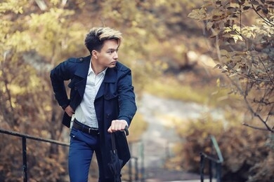autumn park in rainy weather and a young man with an umbrella
