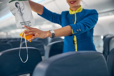 close up portrait of hands of flight attendant on a commercial passenger jet reaching for an oxygen mask
