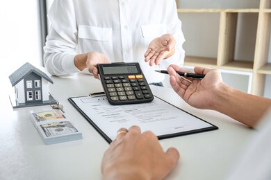 real estate broker agent presenting and consult to customer to decision making sign insurance form agreement, home model, concerning mortgage loan offer for and house insurance.