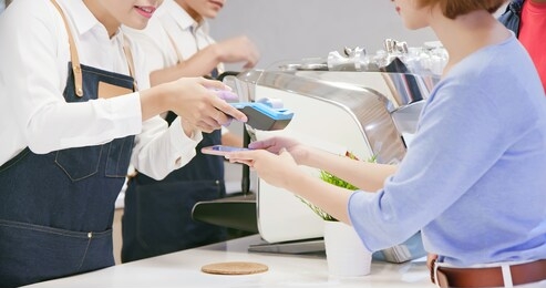 mobile payment concept - woman pays bills by phone to credit card system in the cafe shop