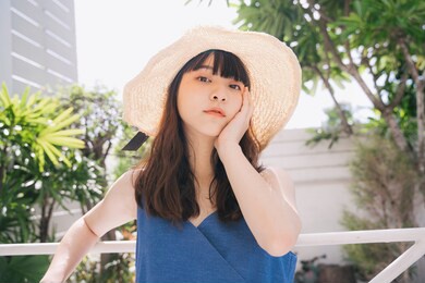 portrait of young asian woman traveler wearing blue dress and hat outdoors in city.
