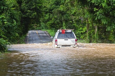 driving through flood water cramped on the road, heavy rains cause wild water to flood the road,motion blur,overuse of noise reduction.