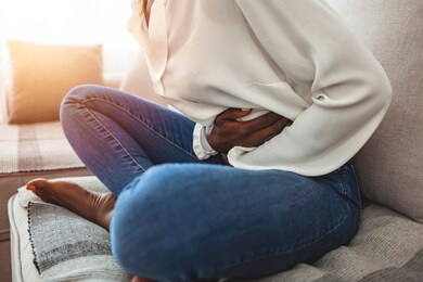 shot of an attractive young woman suffering from stomach cramps at home. young woman suffering from strong abdominal pain while sitting on sofa at home