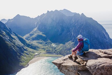 woman hiker enjoying at the top of the mountain and looking at incredible views of a norwegian fjord, lofotens. travel, adventure, healthy lifestyle concept