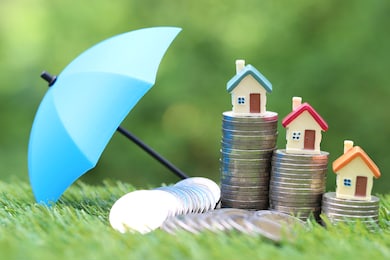 protection, model house on stack of coins money with the umbrella on nature green background,finance insurance and safe investment concept