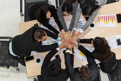 happy business people celebrate teamwork success together with joy at office table shot from top view . young businessman and businesswoman workers express cheerful victory showing unity and support .
