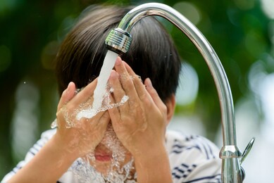 young boy wash his face with water from new faucet at home garden