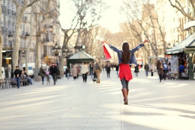 barcelona, la rambla shopping woman. female shopper walking happy away with shopping bags raised up. from the famous landmark street in catalonia, spain.