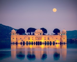 vintage retro hipster style travel image of rajasthan landmark - jal mahal (water palace) on man sagar lake in the evening in twilight.  jaipur, rajasthan, india