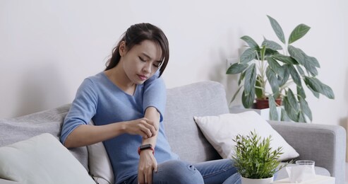 asian beauty woman has dry skin and scratching her elbow in the living room