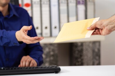 businessman receiving a padded envelope sitting on a desk at office