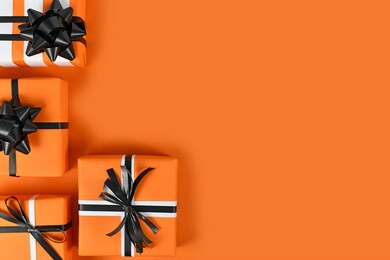 gift boxes with traditional halloween colors on left side of  orange background with empty copy space