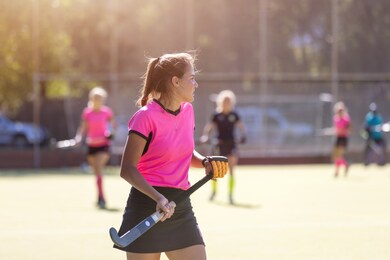 young female field hockey player on the pitch with stick
