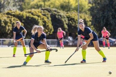two field hockey female players getting the ball for penalty shot