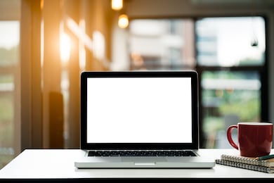 conceptual workspace,laptop computer with blank white screen and notebook and coffee cup on table,in loft restaurant blurred background.