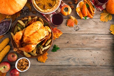 thanksgiving dinner with chicken, cranberry sauce, pumpkin pie, wine, seasonal vegetables and fruits on wooden table, copy space. traditional autumn holiday food concept.