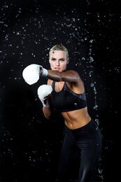 professional caucasian female boxer  sportswoman posing in aqua studio against black background. vertical image