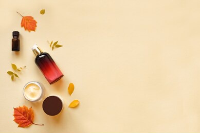 autumn skin care products and autumn leaves on yellow background, flat lay, copy space.  seasonal beauty routine and organic cosmetic concept.