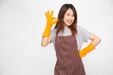 portrait of young asian woman wearing orange rubber gloves for hands protection during cleaning and showing ok sign isolated over white background